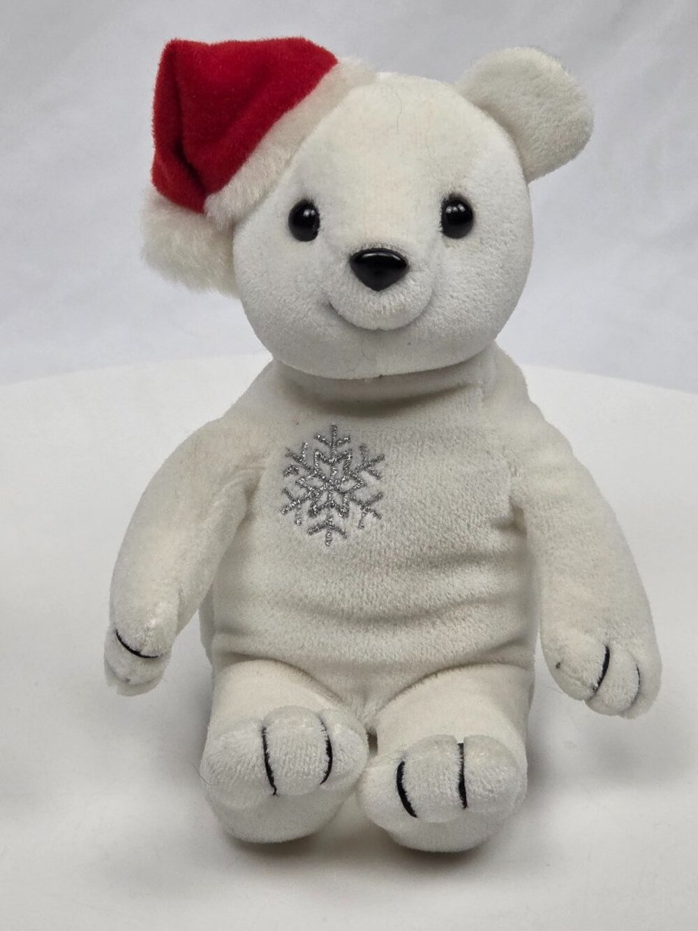 white plush holiday teddy bear wearing a small red Santa hat 8"